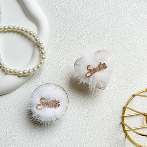 Close-up of heart-shaped white plush phone grip with a sparkling gold Smile rhinestone
