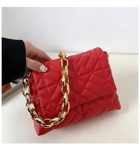 Detailed view of red quilted PU leather shoulder bag with chunky gold acrylic chain