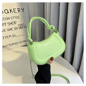 Detail of a bright green baguette bag with knotted handle and silver chain strap