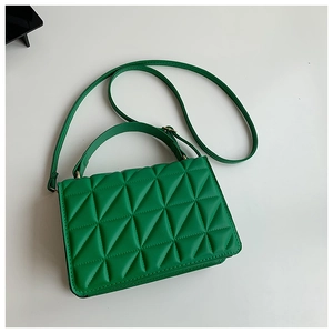 Detail of green quilted handbag with triangle stitching pattern and golden hardware