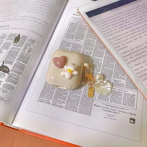 Detailed shot of cream AirPods case featuring a 3D cat, pink heart and pearl shell charm