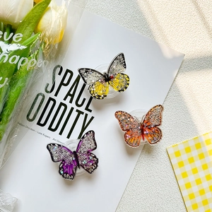 Macro detail of butterfly resin phone grips with sparkling star sequins and glitter infills