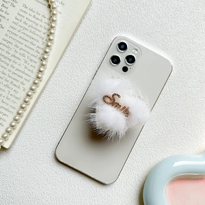 White heart plush phone socket grip with rhinestone Smile lettering on a smartphone