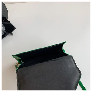 Detail view of the green crossbody bag showing open flap and black interior compartment