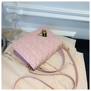 Detailed view of pink quilted PU leather handbag with gold metal lock on silk background