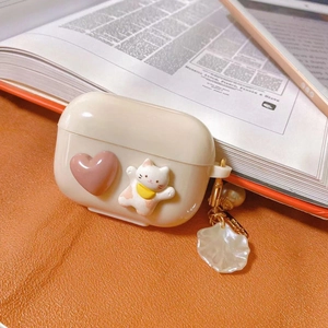 Detail of cute cat and pink heart earphone case with pearl and shell keychain pendant