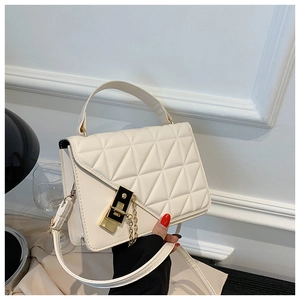 Detail of cream quilted handbag featuring gold metal clasp and versatile shoulder strap
