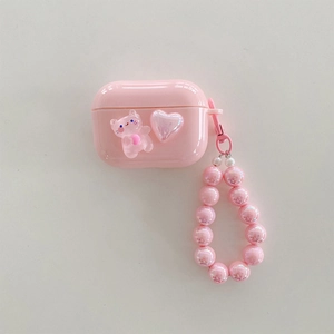 Detailed view of pink AirPods case featuring a 3D bear, heart icon, and beaded wrist strap