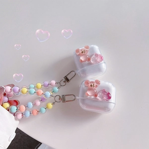 Detail of clear AirPods case with pink 3D bear, glitter heart, and colorful beaded lanyard