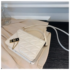Detail of cream quilted PU leather handbag with gold metal lock and elegant chain strap