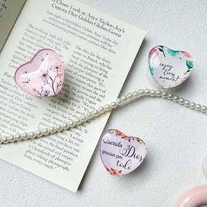Macro shot of heart-shaped acrylic phone grips with floral designs and motivational text