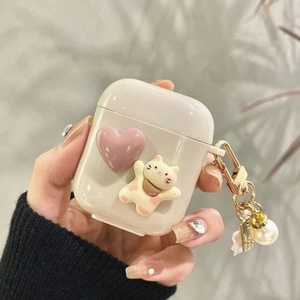 Close-up of creamy white AirPods case with 3D lucky cat, pink heart and pearl keychain
