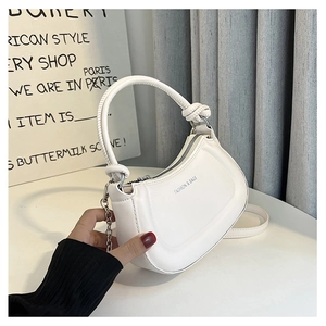 Detailed view of white semi-circular handbag with knot handle and metal chain detail