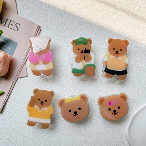 Detail showing various cute cartoon bear acrylic phone grips on decorative background