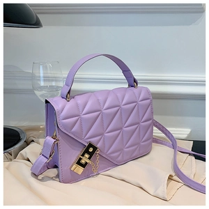 Macro detail of purple quilted crossbody bag with golden square lock on silk fabric