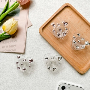 Detail of four heart-shaped phone grips with pink and white rhinestones on white background
