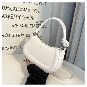 Close-up of a white leather bag featuring a round handle, side knots, and logo lettering