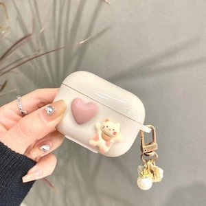 Detail of cute cat and pink heart on creamy white AirPods Pro case with pearl charm