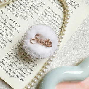 Detailed macro of a plush white phone socket with rhinestone Smile text and pearl chain