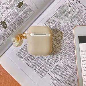 Detailed macro of beige matte AirPods case with elegant pearl and seashell gold keychain charm