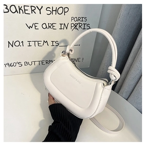 Close-up of stylish white handbag with a unique knotted handle and zipper detail