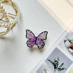 Macro shot of purple glitter butterfly phone grip with star sequins and silver sparkles