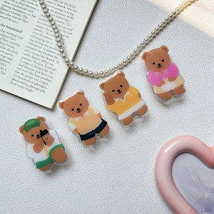 Detail shot of four cute acrylic bear phone stands in various colorful outfits and poses