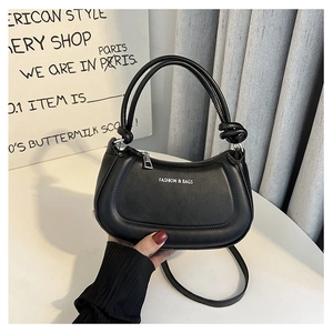 Detail view of black PU leather handbag showing knotted handles and white fashion text logo