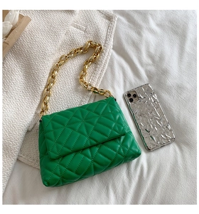 Detailed view of green quilted handbag with chunky gold chain strap and smartphone for scale