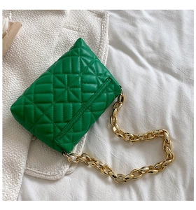 Detail of green quilted shoulder bag featuring chunky gold acrylic chain and soft PU texture