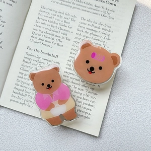 Close-up of cute acrylic bear phone grip set on an open book in a cozy setting
