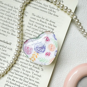 Detail eines herzförmigen Handy-Halters mit lila Aquarell-Blumenmuster-Dekor