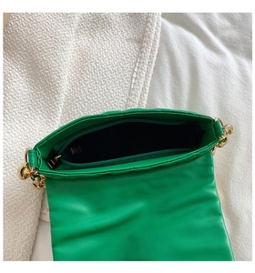 Detail view of the green quilted bag interior with a zipper pocket and gold chain strap