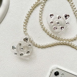 Detail of heart-shaped rhinestone phone grips with white pearl neck strap accessory