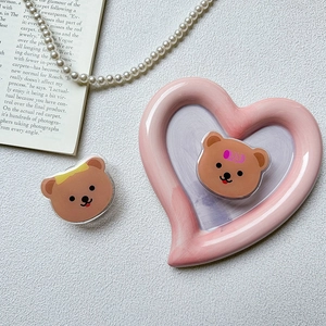 Detail of cute bear acrylic phone grip set on a pink heart ceramic tray and white background