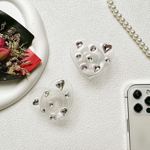 Close-up of heart-shaped rhinestone phone grips with crystals on a textured white background