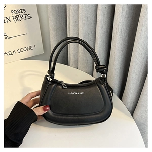 Detail of black leather crescent bag with white Fashion & Bags text and knotted handle