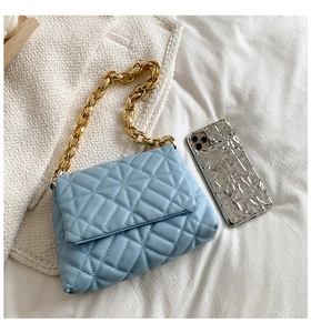Detail of light blue quilted shoulder bag with premium golden acrylic chain strap