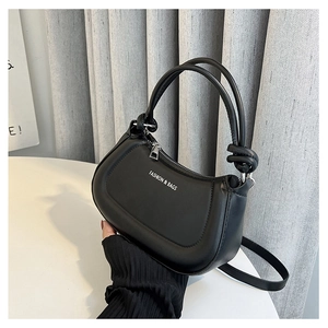 Close-up of black matte synthetic leather handbag featuring FASHION & BAGS text and knotted handle