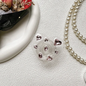 Close-up of heart-shaped phone grip with pink rhinestones and a romantic rose background