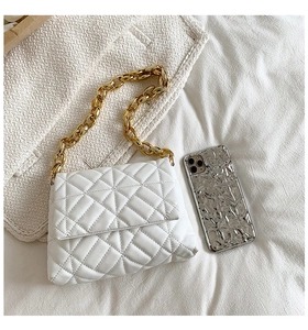 Detailed macro view of white quilted PU leather handbag with chunky gold acrylic chain strap