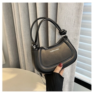 Detail of a black leather handbag with a knotted handle and silver chain strap
