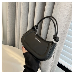 Close-up of black leather handbag with metal zipper and unique knot handle detail