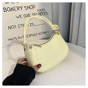 Detail of light yellow crescent bag with knotted handle and elegant metal chain strap
