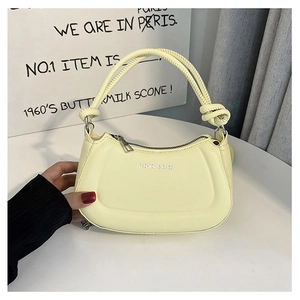 Detail of cream leather handbag featuring knotted handle and fashion text logo