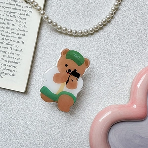 Close-up of cute acrylic bear phone socket with green hat on a decorative background