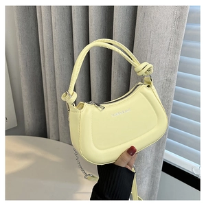 Detail of light yellow semicircular handbag with silver zipper and chain strap