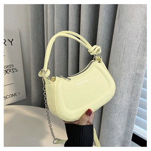 Detail of light yellow crescent bag featuring a tied handle and gold chain strap