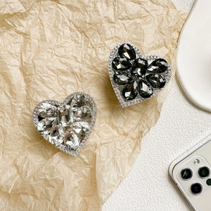 Close-up of heart-shaped rhinestone phone grips in silver and grey gems on paper
