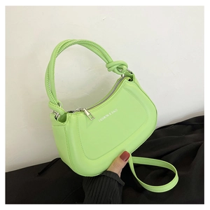 Detail view of neon green semi-circular saddle bag with braided handle and silver zipper